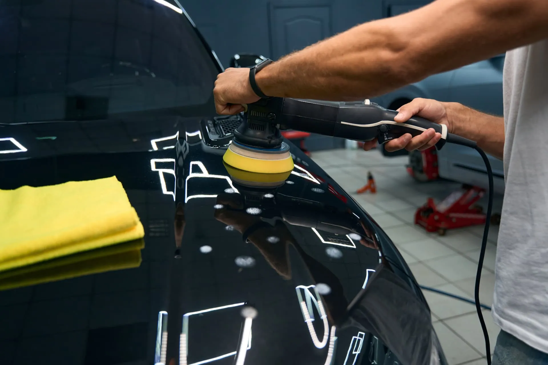 Detailer machine-polishing a black car hood before ceramic coating in Rhode Island