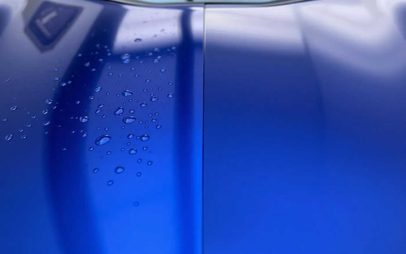 Beaded water on a ceramic-coated car hood next to a wax-finished panel